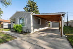 Manufactured / mobile home with fence, driveway, an outdoor structure, and an attached carport