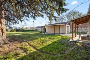 View of yard featuring an outdoor structure, fence, and a patio