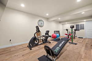 Workout room with recessed lighting, baseboards, electric panel, and hardwood / LPV laminated wood floors