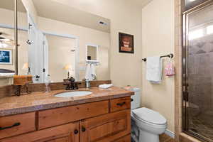 Ensuite bathroom in bedroom #2 with fan, a stall shower, vanity, and toilet