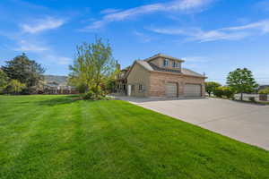 View of side of house featuring driveway, a front yard, a garage, brick siding, and stucco siding