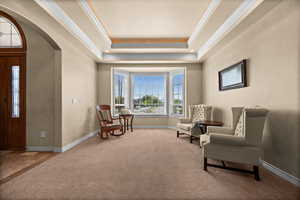 Living area with arched walkways, ornamental molding, carpet, and baseboards