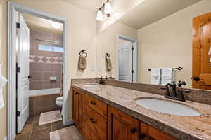 Full bathroom with double vanity, toilet, a sink, and tile patterned flooring