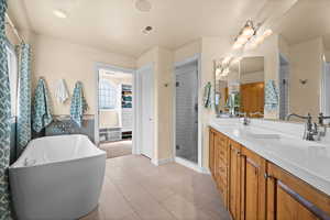 Bathroom featuring, double vanity, a shower stall, a sink, free standing tub and a wealth of natural light