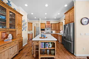 Kitchen featuring open shelves, ornamental molding, baseboards, arched walkways, and stainless steel appliances