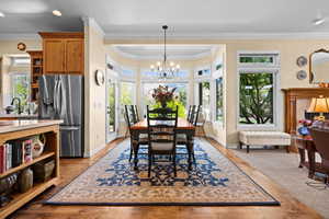 Dining room featuring crown molding, baseboards, wood finished floors, and a chandelier