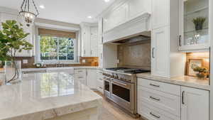 Kitchen featuring a sink, recessed lighting, white cabinetry, and range with two ovens