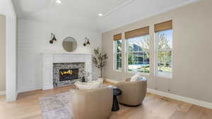 Living area with baseboards, visible vents, light wood-style flooring, and lofted ceiling