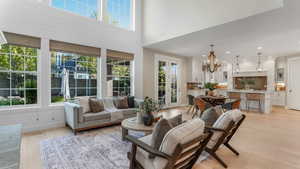 Living room with a notable chandelier, a wealth of natural light, and light wood finished floors