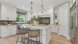 Kitchen featuring light wood-style flooring, appliances with stainless steel finishes, and white cabinetry