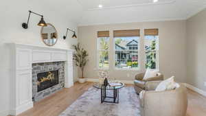 Living area featuring baseboards, a fireplace, vaulted ceiling, and light wood finished floors