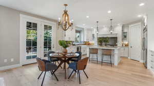 Dining area with recessed lighting, light wood-style flooring, baseboards, and a notable chandelier