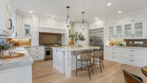 Kitchen featuring recessed lighting, white cabinetry, tasteful backsplash, and premium appliances