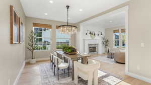 Dining area with a notable chandelier, light wood finished floors, a glass covered fireplace, recessed lighting, and baseboards