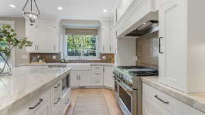 Kitchen with a sink, premium range hood, recessed lighting, and double oven range