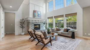 Living room with a fireplace, hardwood / wood-style floors, baseboards, a towering ceiling, and visible vents