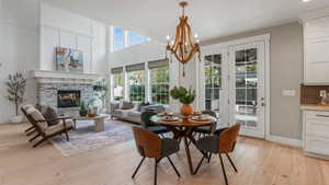 Dining room with baseboards, a fireplace, light wood-style flooring, and a notable chandelier