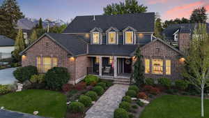 View of front of home featuring a porch, a lawn, brick siding, and roof with shingles