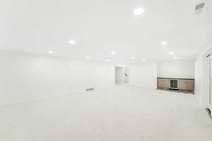 Below grade area featuring light carpet, beverage cooler, recessed lighting, baseboards, and visible vents