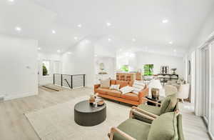 Living area featuring high vaulted ceiling, baseboards, and light wood-type flooring