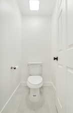 Bathroom with baseboards, tile patterned floors, and toilet