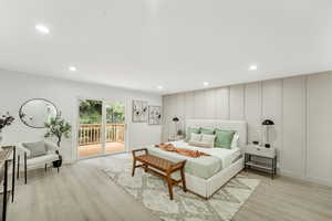 Bedroom with access to outside, light wood-style floors, recessed lighting, and a decorative wall