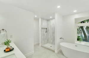 Full bathroom with a freestanding bath, baseboards, tile patterned floors, and recessed lighting