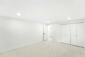 Unfurnished bedroom featuring recessed lighting, light colored carpet, and a closet