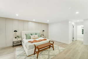 Bedroom featuring recessed lighting, baseboards, light wood finished floors, and a decorative wall