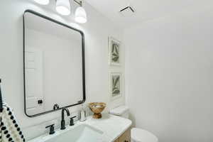 Bathroom featuring visible vents, toilet, and vanity