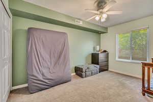 Carpeted bedroom with visible vents, baseboards, ceiling fan, and a closet