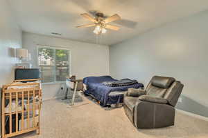 Carpeted bedroom with visible vents, baseboards, and ceiling fan