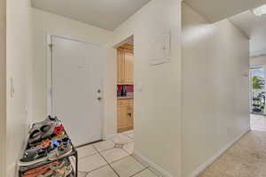Corridor featuring light tile patterned flooring, baseboards, and electric panel