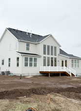 Back of house featuring roof with shingles, central AC, and a deck
