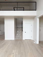 Interior space featuring light wood finished floors, visible vents, a towering ceiling, and baseboards