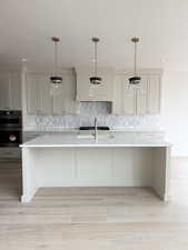 Kitchen featuring light countertops, a textured ceiling, multiple ovens, and decorative backsplash
