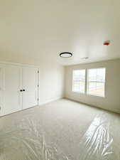 Empty room featuring light carpet, baseboards, visible vents, and a textured ceiling