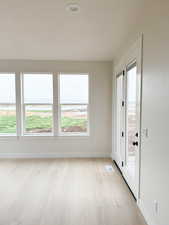 Unfurnished room with a wealth of natural light, baseboards, visible vents, and light wood-style flooring