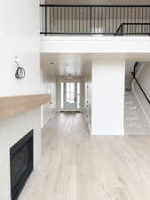 Unfurnished living room featuring a towering ceiling, wood finished floors, baseboards, a tiled fireplace, and stairs