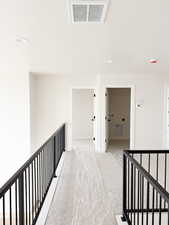Hall with recessed lighting, visible vents, an upstairs landing, a textured ceiling, and light colored carpet