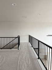 Hall featuring an upstairs landing, a textured ceiling, baseboards, carpet flooring, and visible vents