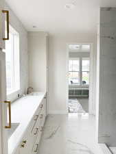Bathroom with baseboards, marble finish floor, a sink, and double vanity