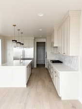 Kitchen with white cabinets, light countertops, a sink, and light wood-style flooring