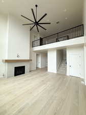 Unfurnished living room with a towering ceiling, visible vents, wood finished floors, stairway, and a tile fireplace