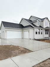 View of front facade featuring board and batten siding, an attached garage, driveway, and a shingled roof