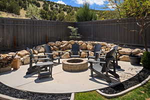 View of patio featuring a fenced backyard, an outdoor fire pit, and a wooded view