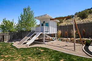 View of play area featuring a lawn and a fenced backyard