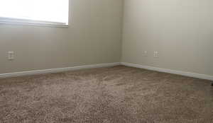 Carpeted empty room featuring baseboards