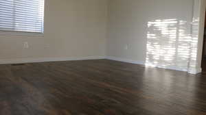 Spare room with visible vents, dark wood finished floors, and baseboards