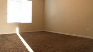 Carpeted spare room featuring baseboards